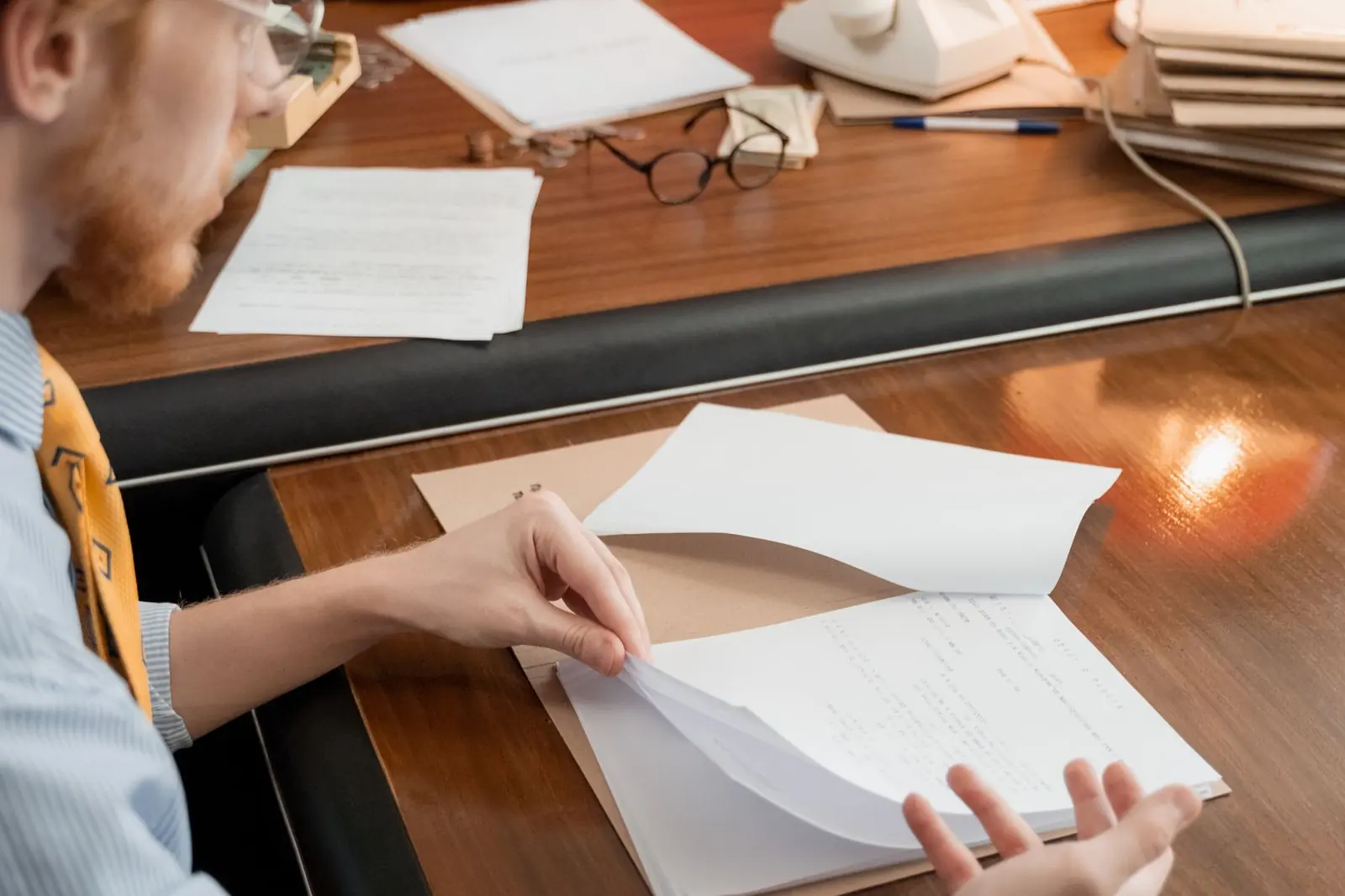 Dos personas repasando juntas unos documentos escritos a mano sobre la mesa de un despacho